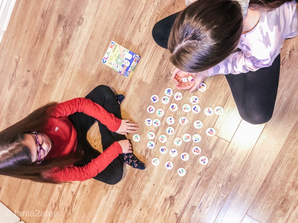two girls playing game, one holding dice and the other waiting her turn
