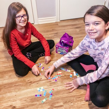 two girls playing domino game with coloured pieces