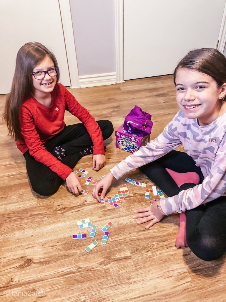 two girls playing domino game with coloured pieces