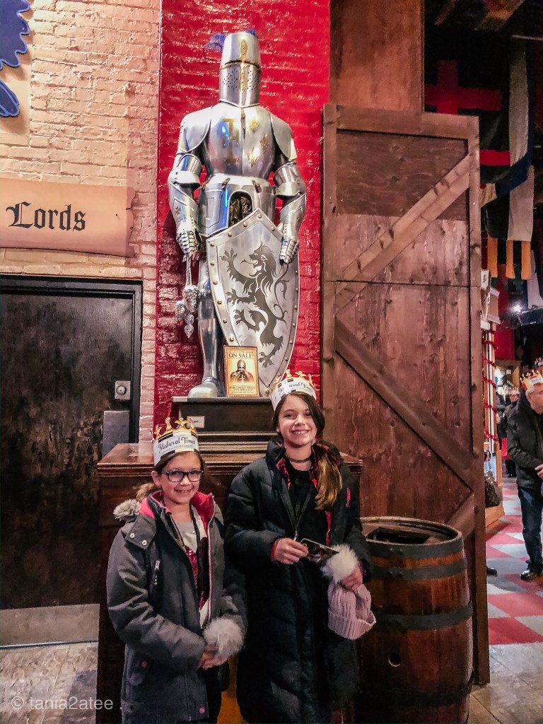 two-girls-at-Medieval-Times-in-front-of-knight-of-armour